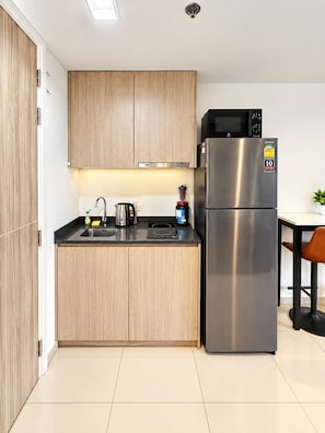Een moderne keuken met houten kastjes, een roestvrijstalen koelkast, een magnetron en een waterkoker.