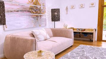 A modern living room with a sofa, a round coffee table, and a large abstract painting.