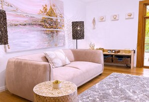 A modern living room with a sofa, a round coffee table, and a large abstract painting.