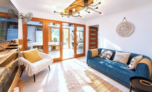 Ein modernes Wohnzimmer mit einem blauen Sofa, einem weißen Sessel und einem Holztisch.