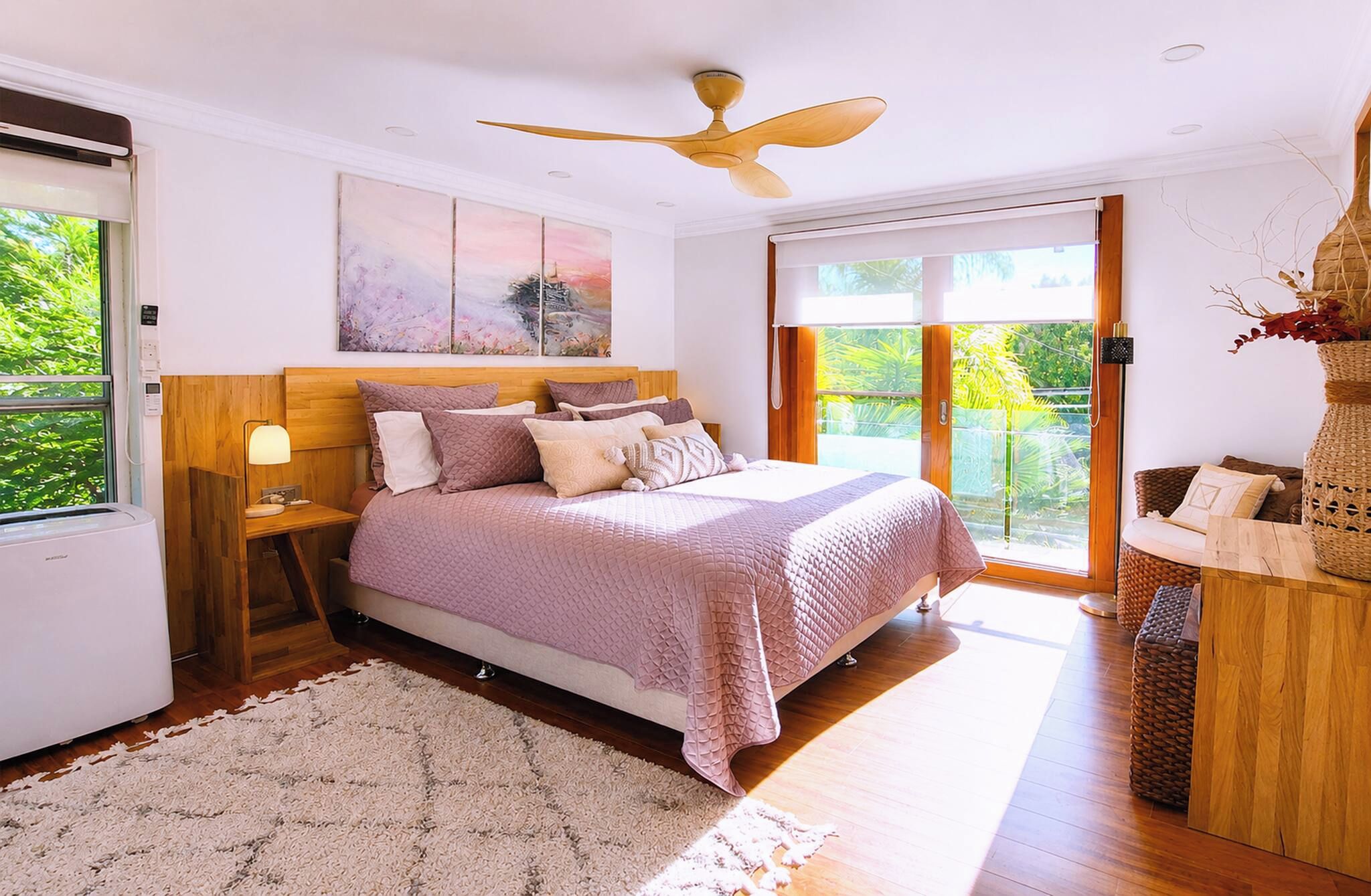 Une chambre à coucher avec un lit, un ventilateur de plafond, une fenêtre donnant sur un beau paysage et une table de chevet.