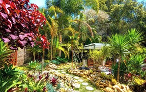 A garden with a variety of plants, a gazebo, and a seating area with chairs. - Palm Beach centre! In & Outdoor Spa! Ocean beach (Palm Beach)