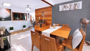 A dining area with a wooden table and chairs, a ceiling fan, and a painting on the wall.