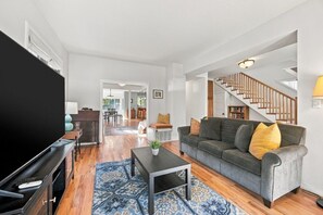 A living room with a television, sofa, coffee table, and patterned rug. - Eight Seventeen Abode | Near UM & Downtown (Missoula)