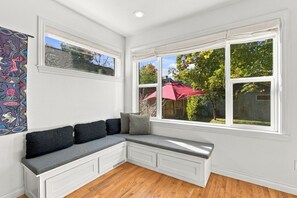 A corner room with a built-in bench, large windows, and a view of the outdoors. - Eight Seventeen Abode | Near UM & Downtown (Missoula)