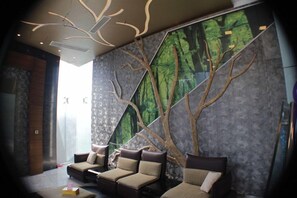 A modern interior with a seating area, a large wall mural, and a unique ceiling design. - Hotel X Gazipur (Gazipur)