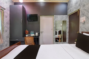 Una camera d'albergo con un letto, una scrivania, una televisione e uno specchio.