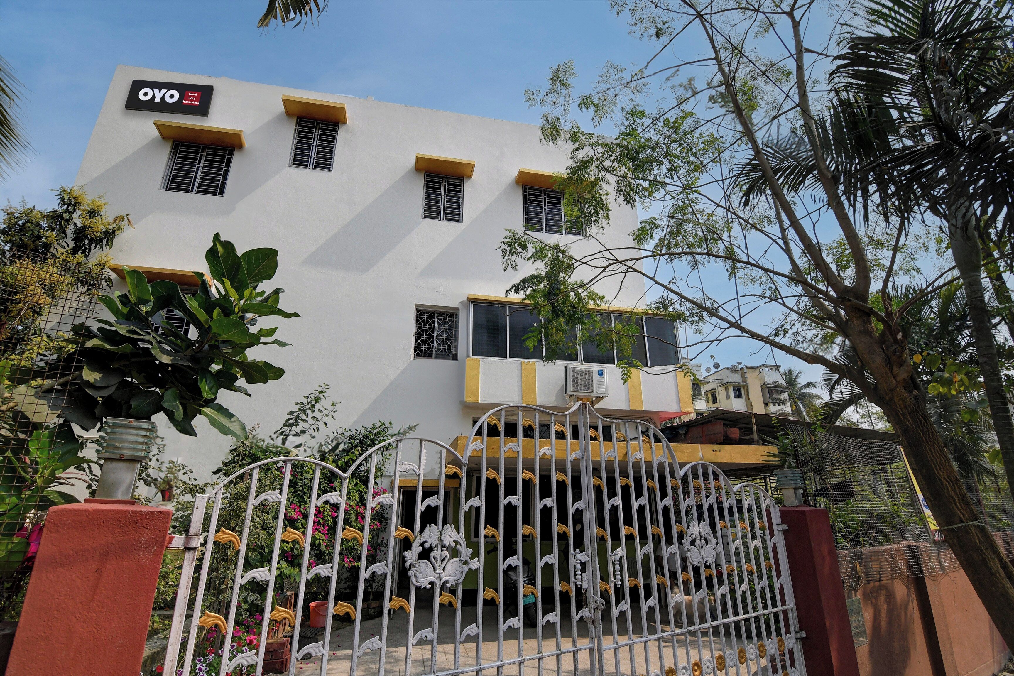 A hotel with a white facade, multiple windows, and a gated entrance with decorative metalwork.