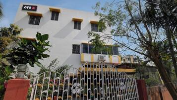 A hotel with a white facade, multiple windows, and a gated entrance with decorative metalwork.