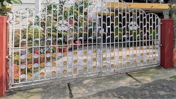 Una entrada protegida por una reja decorativa y plantas con flores.