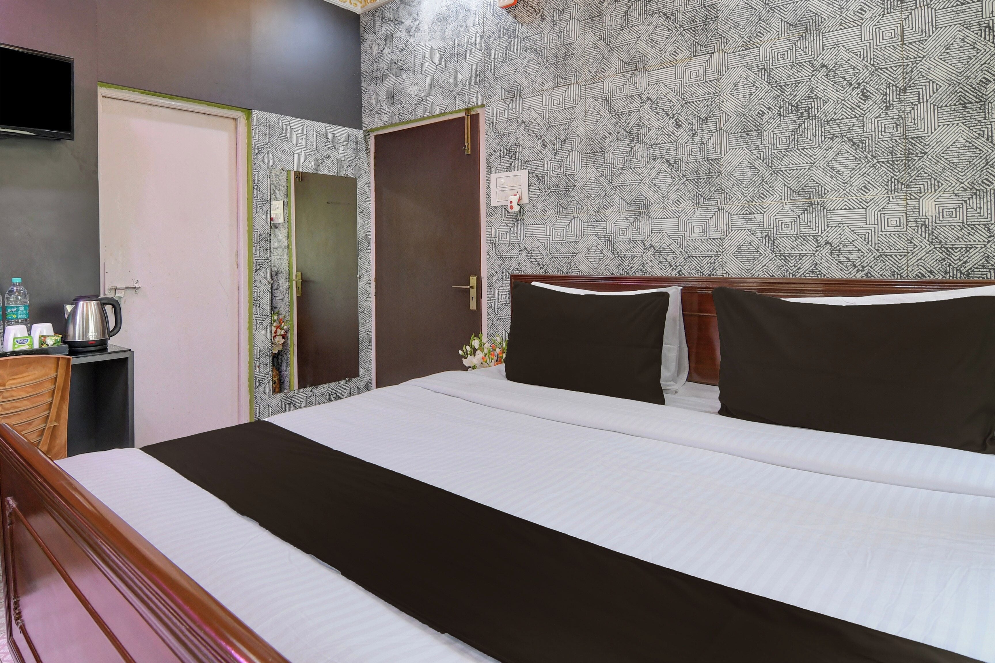 Una habitación de hotel con una cama, una mesita de noche, un televisor y un papel tapiz estampado.