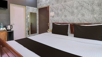 Una habitación de hotel con una cama, una mesita de noche, un televisor y un papel tapiz estampado.