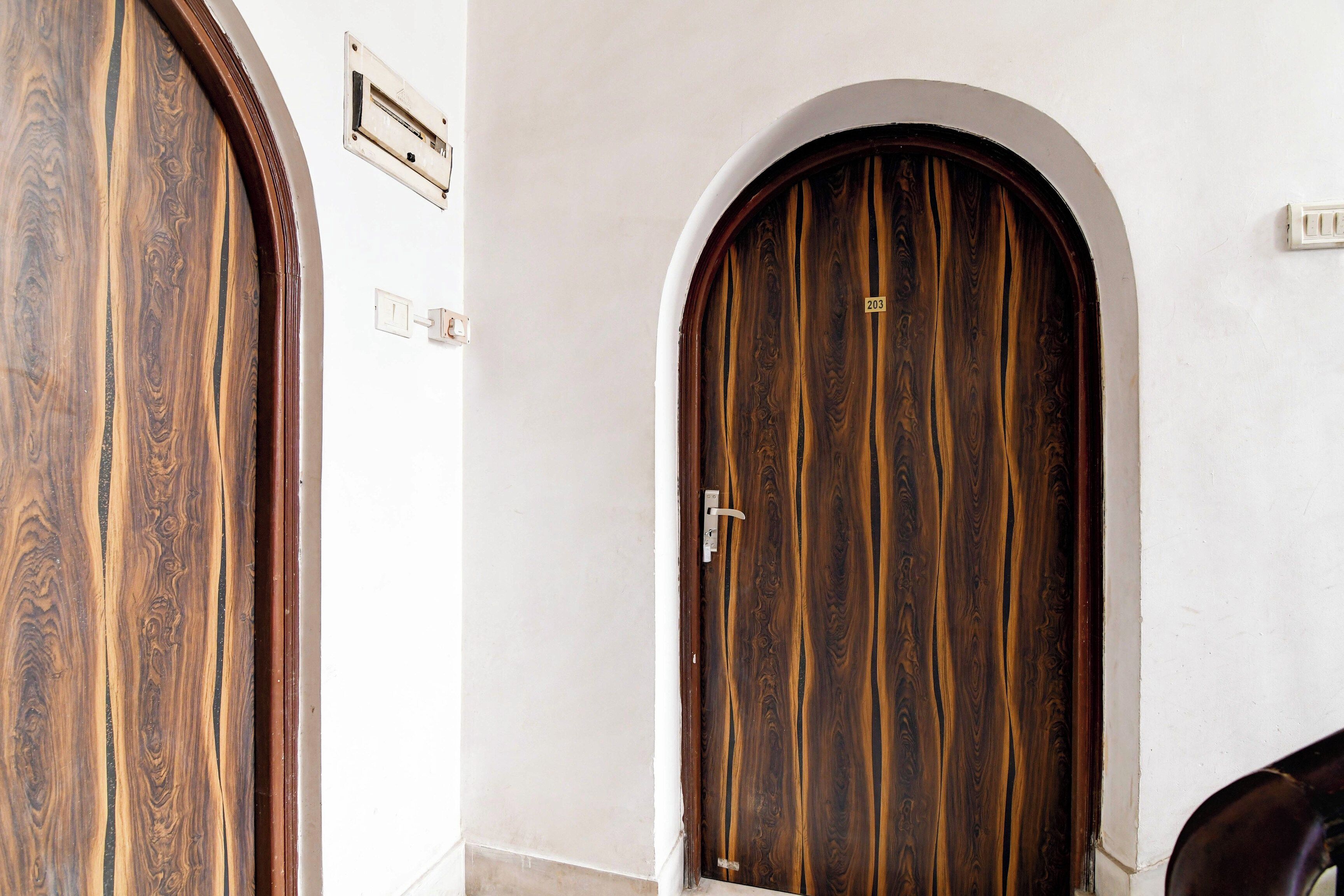 Dos puertas de madera con arcos en la parte superior, una con un picaporte a la vista y el número '203' encima.