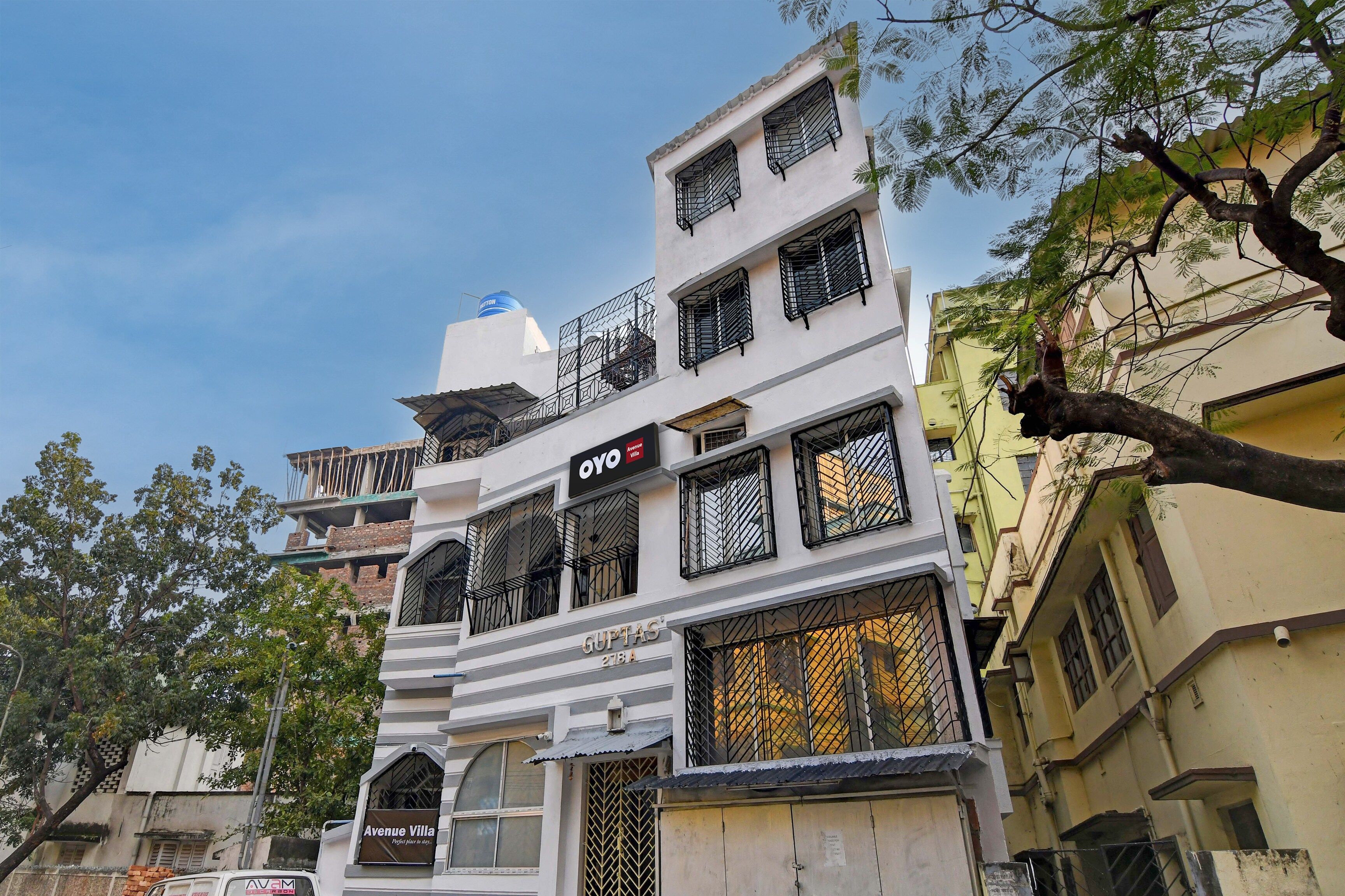 Un edificio de varios pisos con balcones, un cartel que dice 'Avenue Villa' y un depósito de agua en el techo.