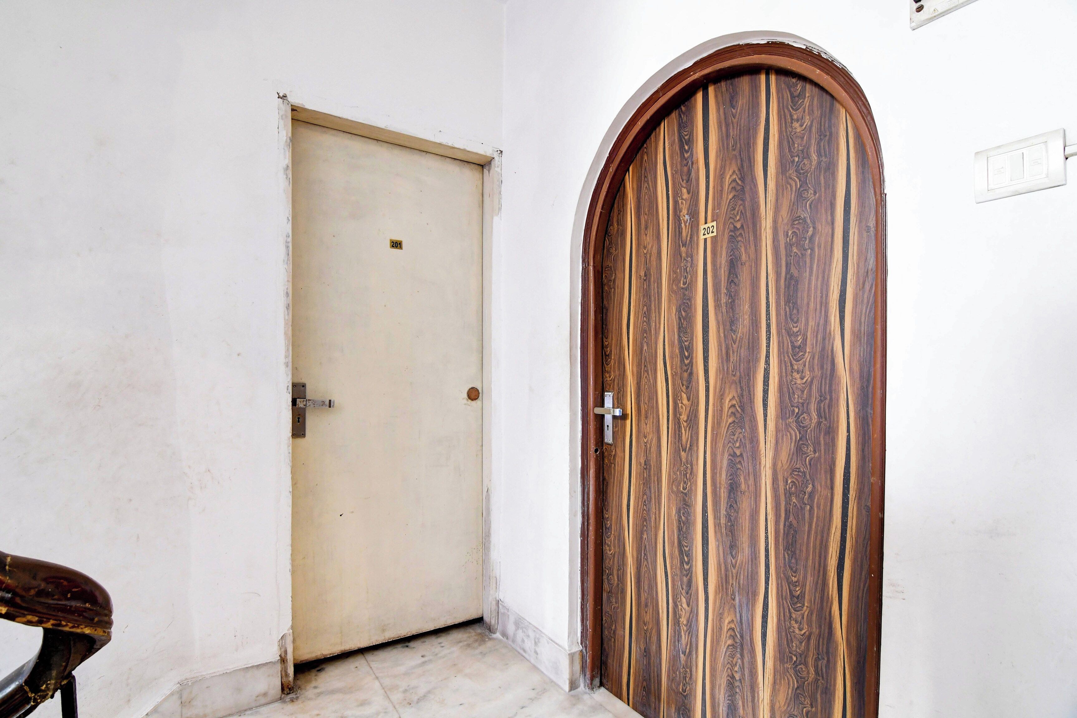 Un pasillo con una puerta lisa y una puerta de madera con una placa numérica.