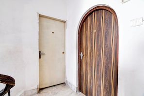 Un pasillo con una puerta lisa y una puerta de madera con una placa numérica.