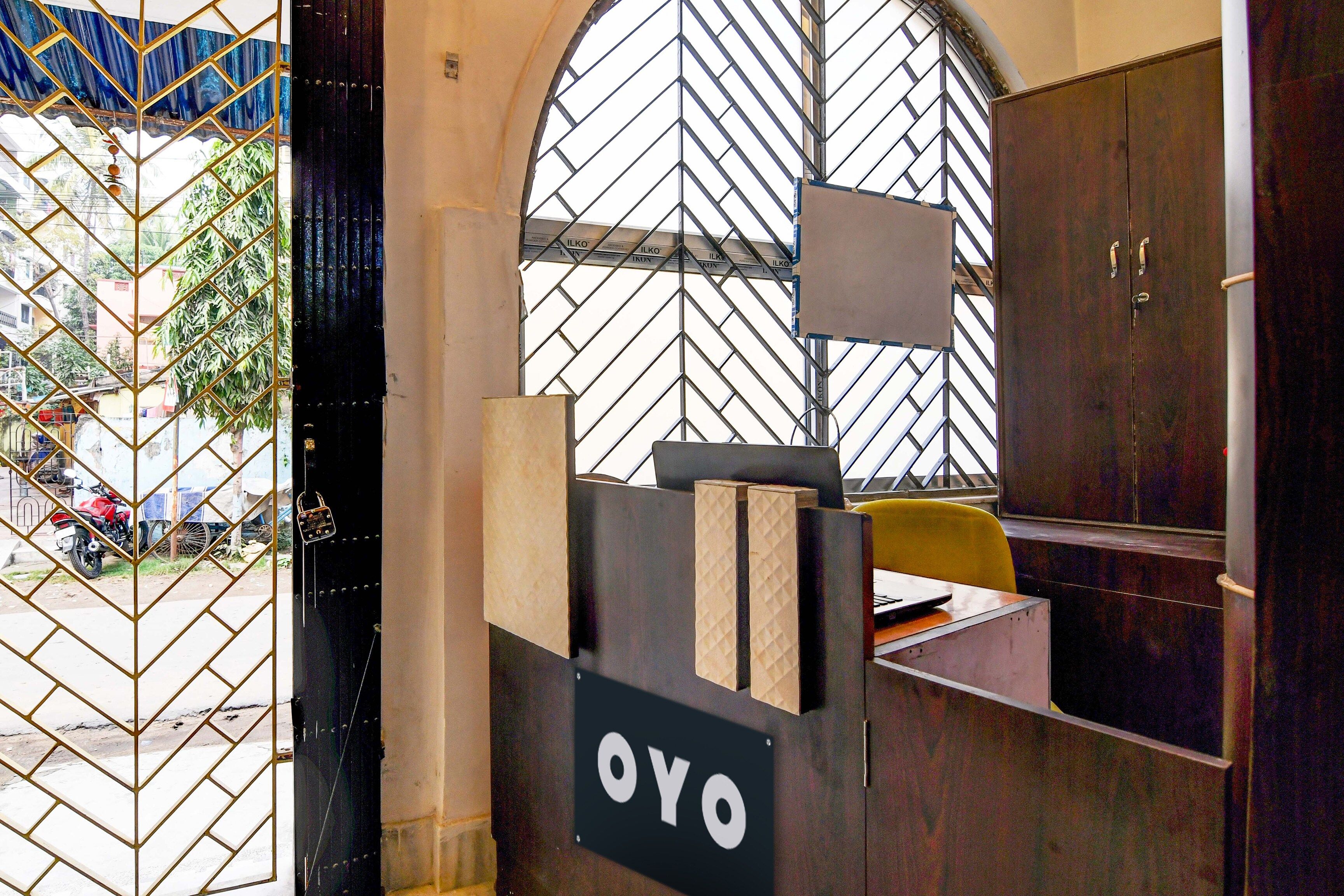 Un mostrador de recepción con un letrero que dice 'OYO' y una ventana con un diseño de celosía metálica.
