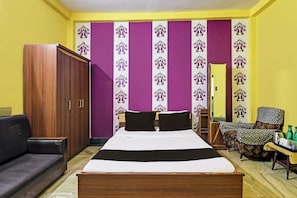 Een kamer met een bed, een kledingkast, een bank en een stoel.