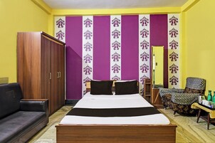 Una habitación con cama, armario, sofá y una silla.