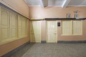 A hallway with cream-colored doors, a black-framed picture frame on the wall, and a small plaque. - Hotel O Arati House (Howrah)