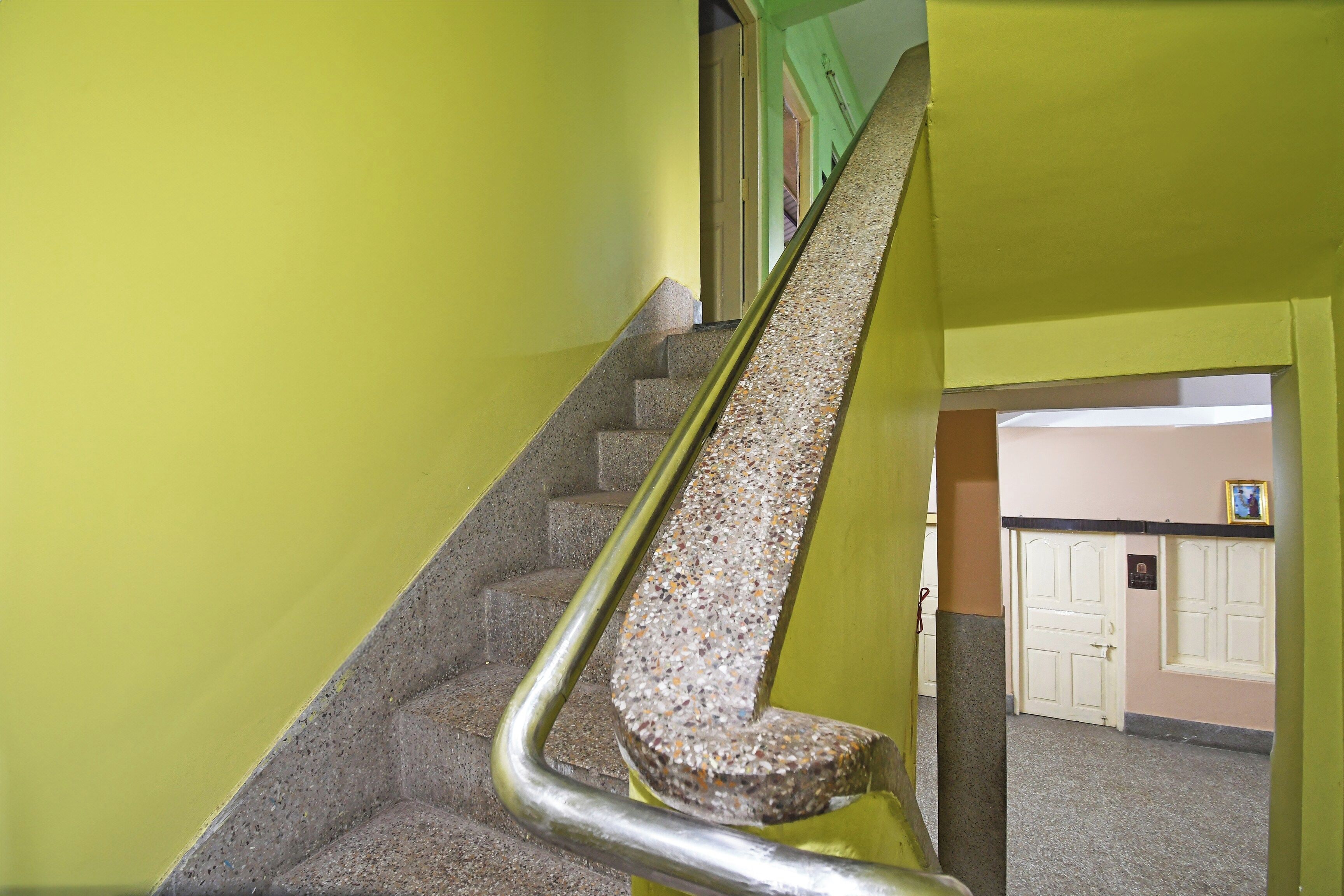 A staircase with a metal handrail and a textured floor.