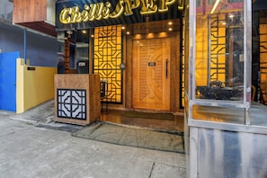 Entrada de un edificio con un letrero que dice 'Chill Shoppe' y una puerta de madera con un cartel que indica que está abierto.