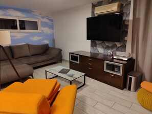 Ein Wohnzimmer mit einer Couch, einem Couchtisch, einem Fernseher und einem Schrank.