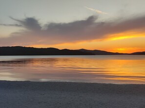A sunset over a calm body of water with distant hills. - Villa A GRAND Poolside Apartment  heating pool (Okrug Gornji)