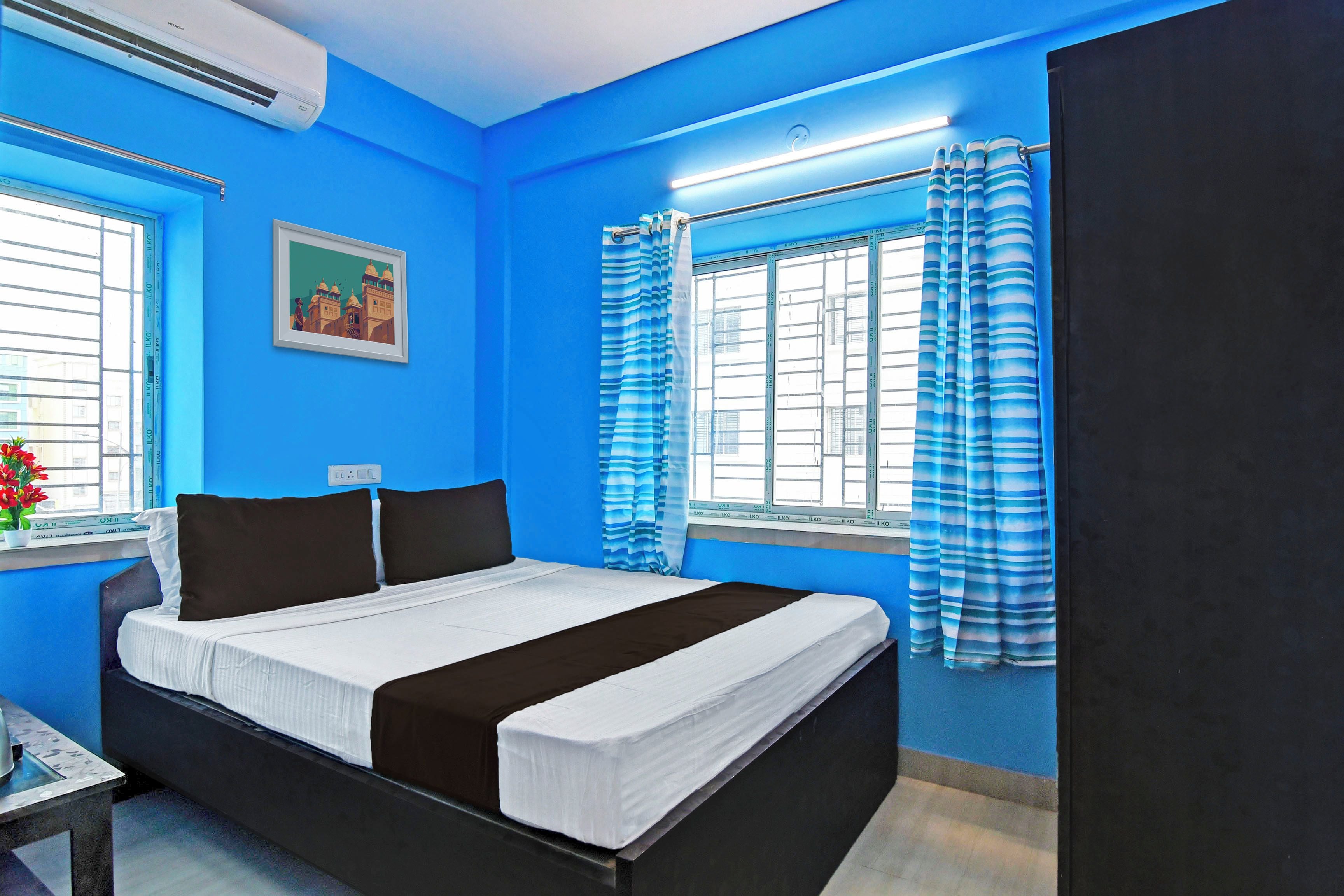 Quarto com cama, janela com cortinas, ar-condicionado fixado na parede e quadro emoldurado.