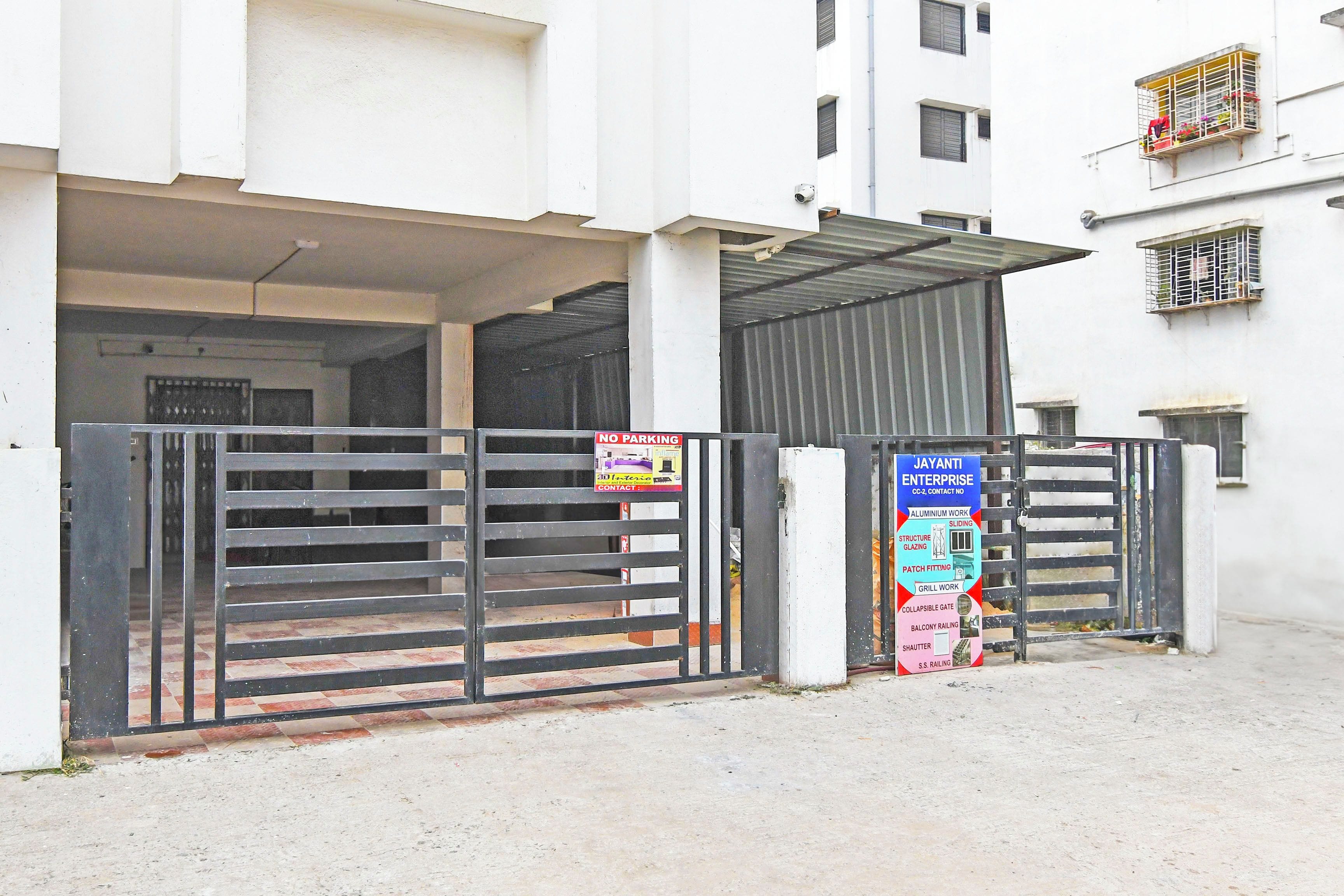 A gated entrance to a building with a metal gate and a signboard listing services like aluminum work and sliding doors.