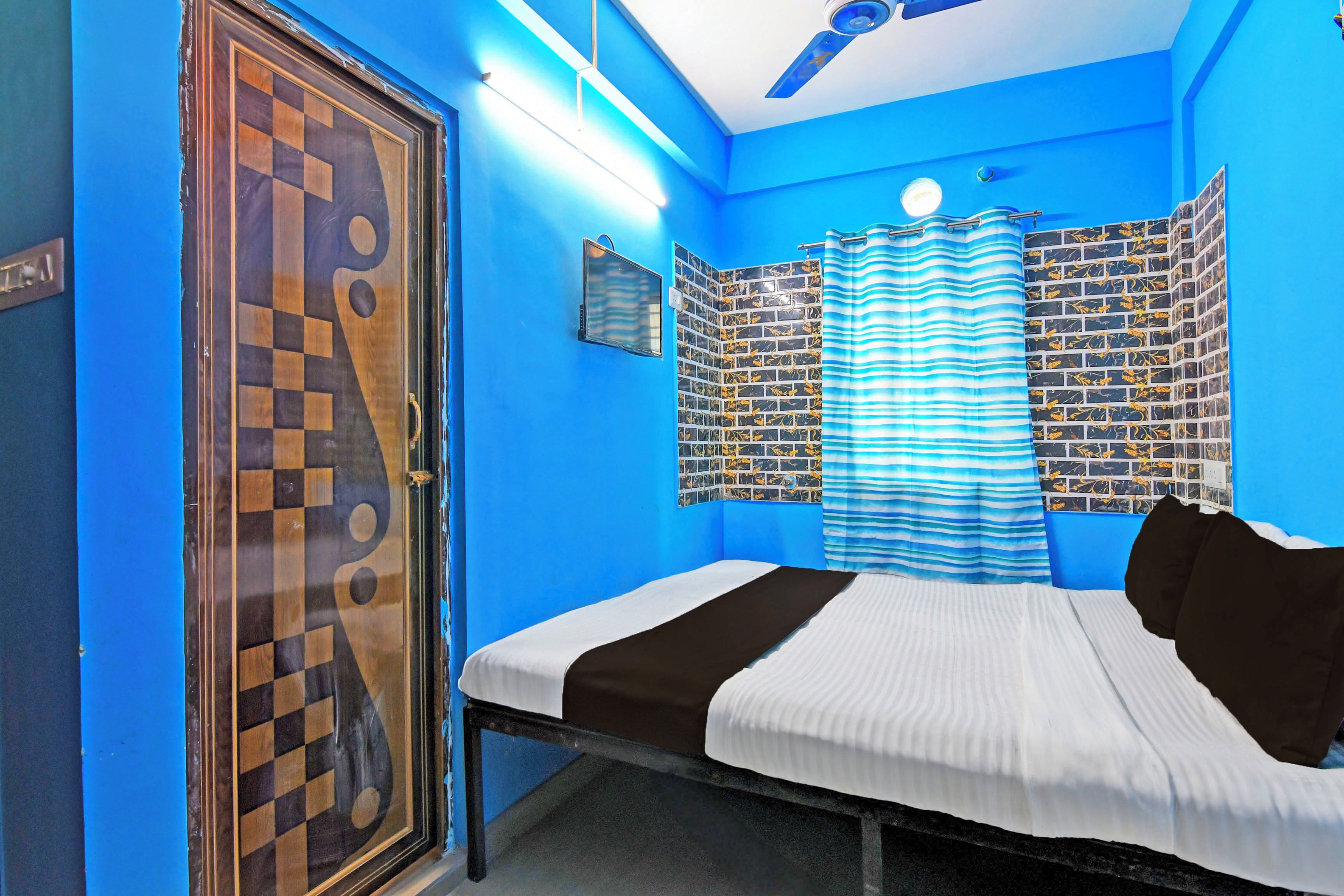 A room with a bed, a window with curtains, a wall with a checkered pattern, and a ceiling fan.