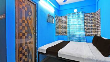 A room with a bed, a window with curtains, a wall with a checkered pattern, and a ceiling fan.
