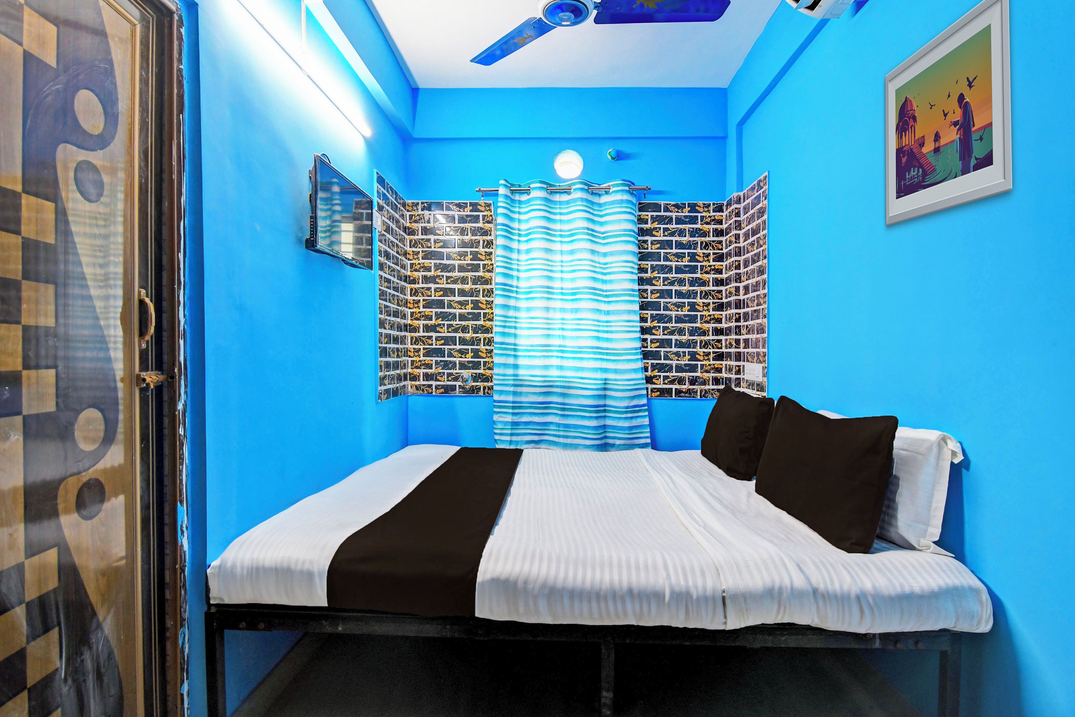 A room with a bed, a window with a curtain, a ceiling fan, and a wall with a patterned design.