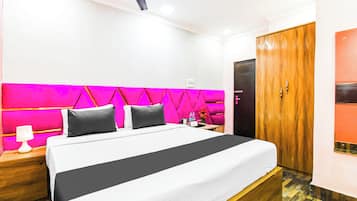 A hotel room with a bed, a nightstand, a lamp, a water bottle, and a wooden wardrobe.