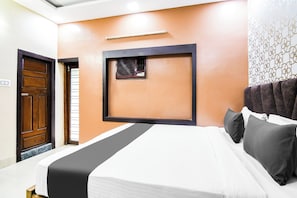 A hotel room with a bed, a wooden door, a window with blinds, and a wall-mounted air conditioning unit. - Hotel O Barsana (Kolkata)