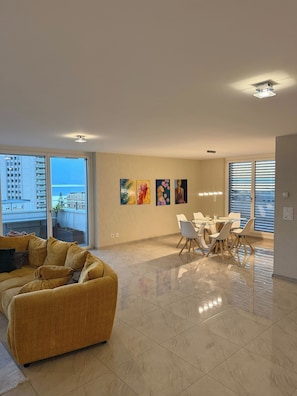 A modern living room with a sofa, dining area with chairs, and artwork on the wall. - Luxurious 4-Bedroom Apartment in Central Montreux (Montreux)