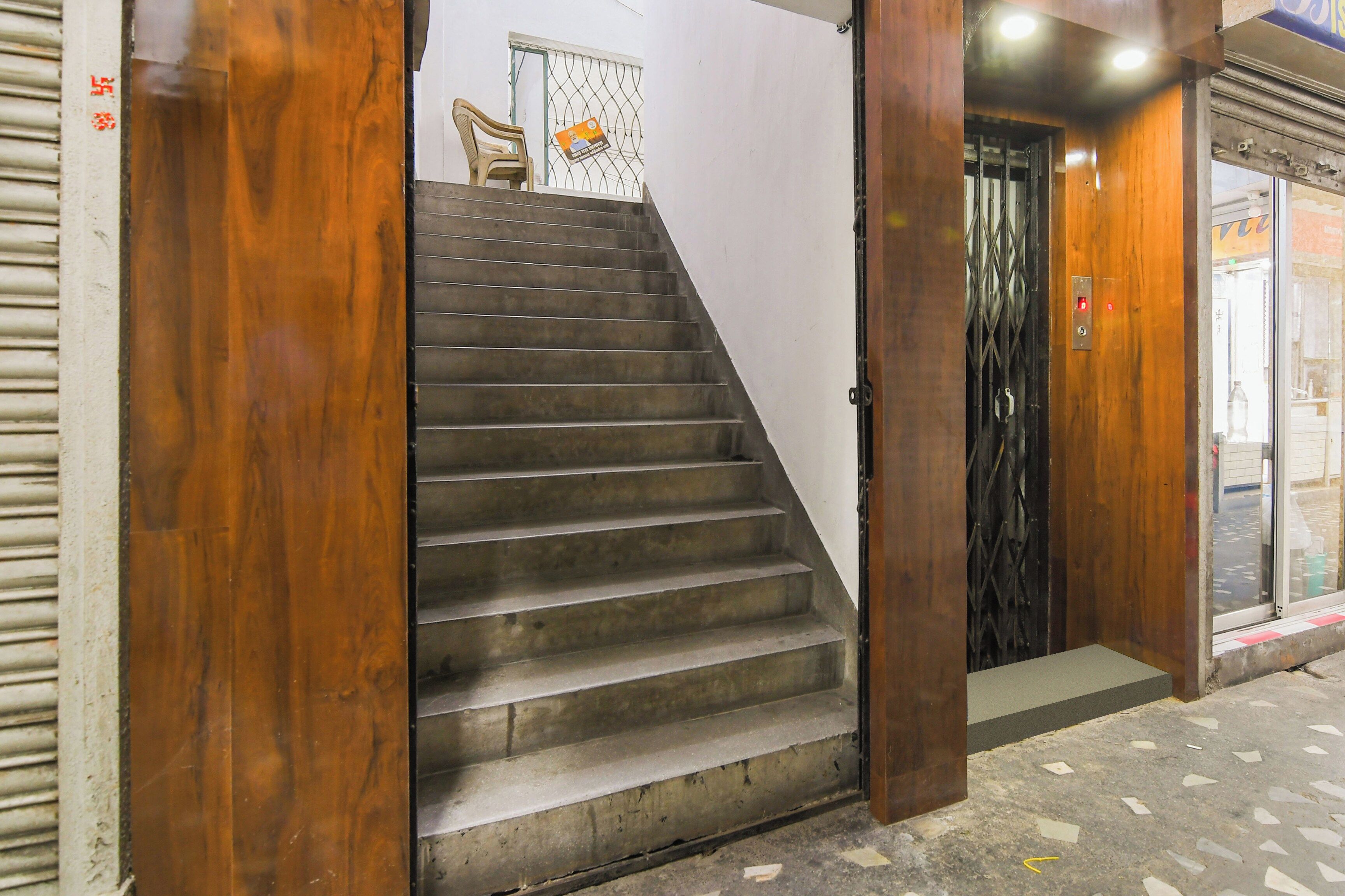 Eine Treppe führt zu einer Tür mit einem Metallgitter, einem Stuhl und einer Wand mit einem Plakat.