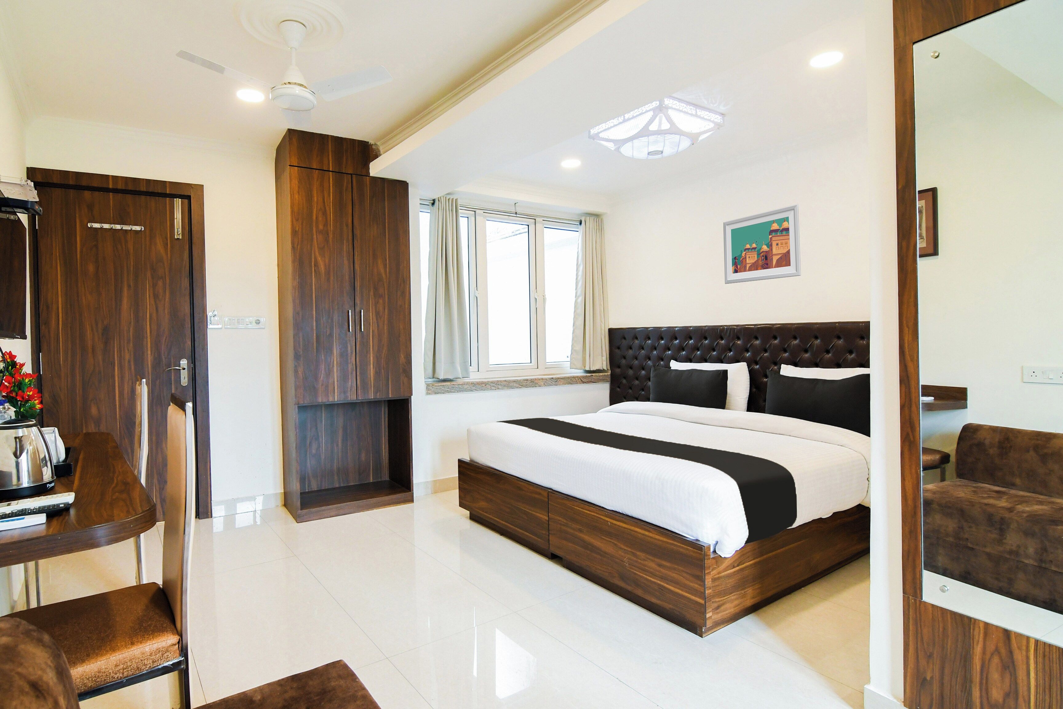 Une chambre à coucher avec un grand lit, un bureau, une chaise, une armoire et un ventilateur de plafond.