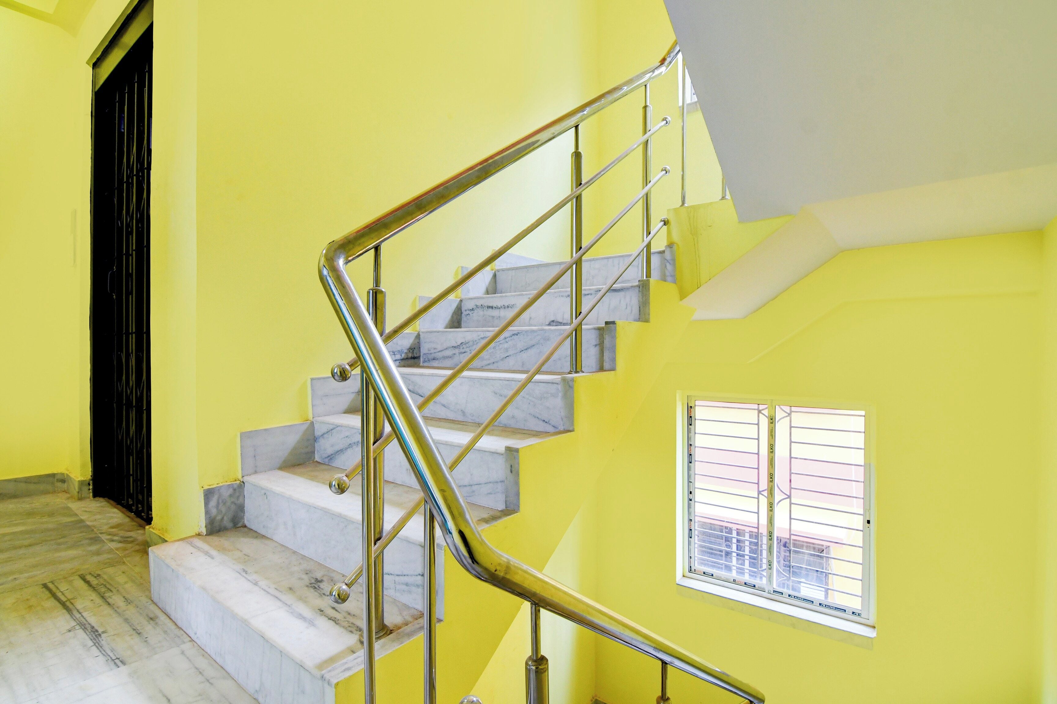 A staircase with marble steps and metal railings, leading to a landing with a window.