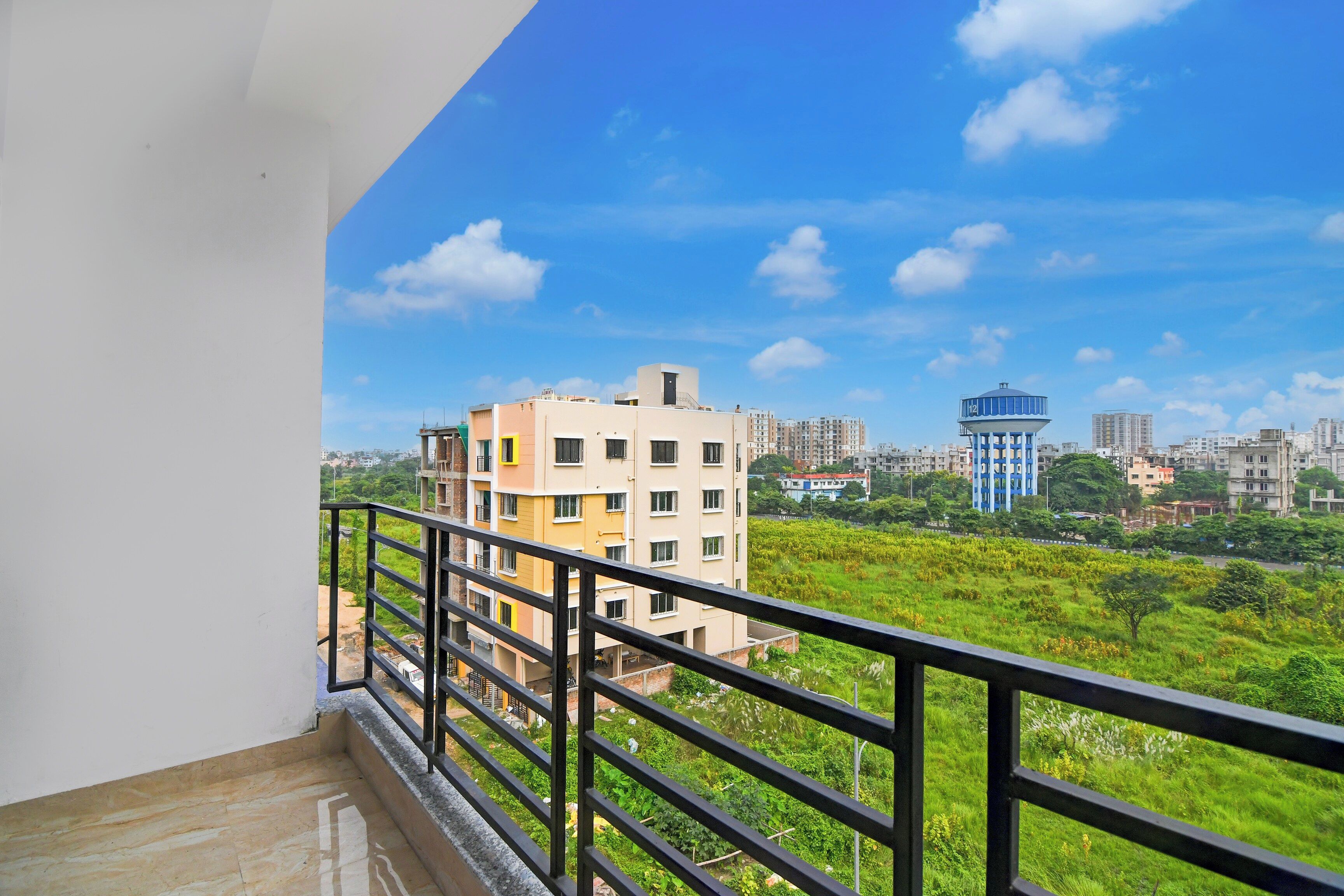 A balcony with a view of a residential area, including a water tower and high-rise buildings.
