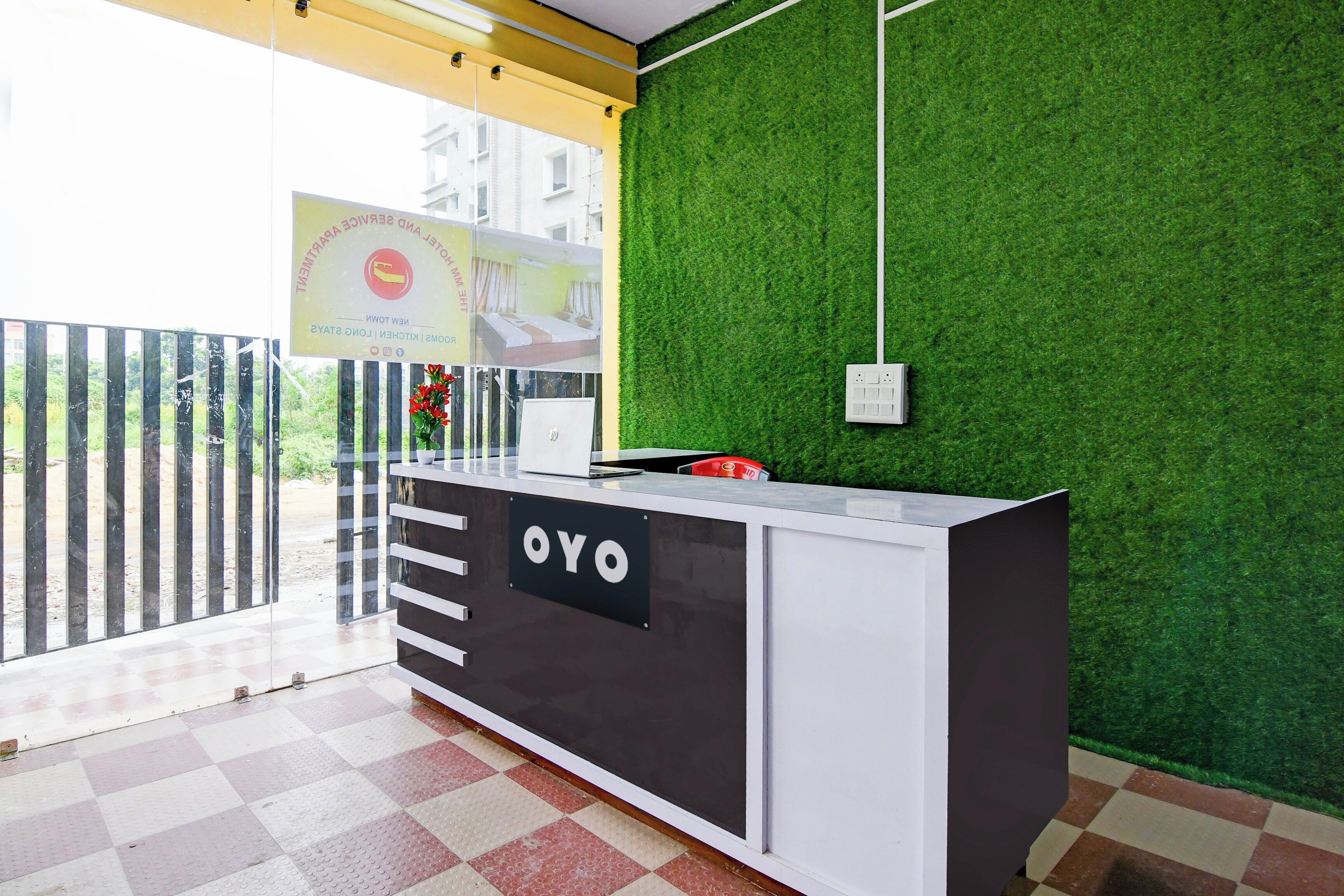 A reception desk with a sign that reads 'OYO' and a green wall with a white ceiling.