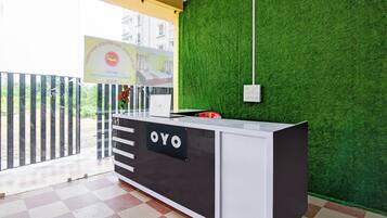 A reception desk with a sign that reads 'OYO' and a green wall with a white ceiling.