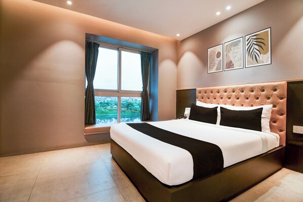 A hotel room with a large bed, a window with curtains, and three framed pictures on the wall. - Collection O Water View Residency (Barasat)