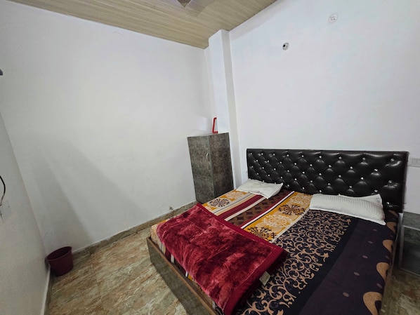 A bedroom with a bed, a red throw blanket, patterned bedspreads, and a grey cabinet. - Hotel O golden shiva (Amritsar)