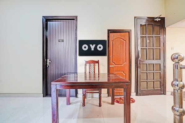 A room with a wooden table and chairs, a door with a number plate, and a sign with the word 'OYO'. - Hotel O PREM VILLA HOME STAY (Amritsar)