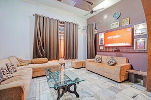 A modern living room with a sofa set, a glass coffee table, and a wall-mounted TV. - Hotel O PREM VILLA HOME STAY (Amritsar)