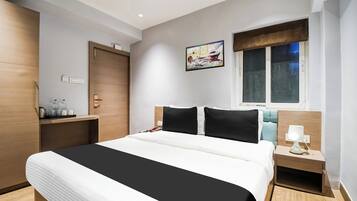 Une chambre d’hôtel avec un lit, une table de chevet, une commode, une fenêtre et une œuvre d’art au mur.