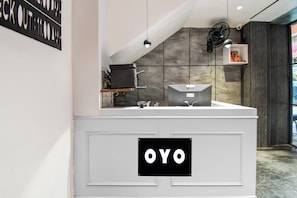 Une salle de bain moderne avec un meuble-lavabo blanc, un miroir et une enseigne noire sur laquelle on peut lire « OYO ».