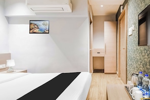 A hotel room with a bed, a bedside table with a lamp, a painting on the wall, a wardrobe, and a bathroom visible through an open door. - Hotel O Sivalika Inn (Kolkata)