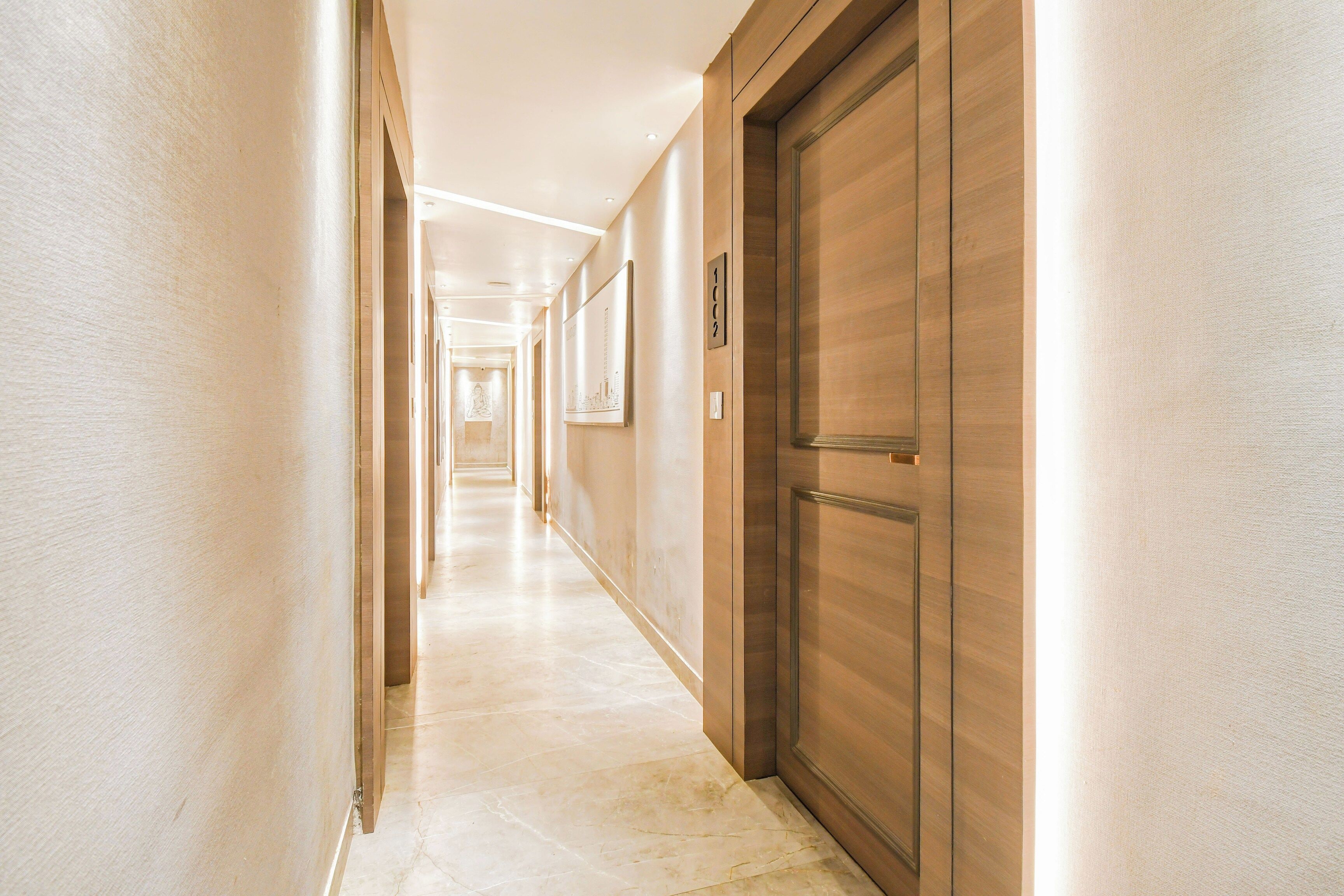 A hotel hallway with a wooden door, a framed picture, and a sign indicating room number 1002.